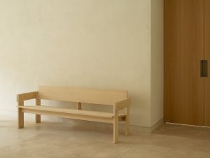 Oak bench in front of a wall. Foeppl Collection by Relvaokellermann for Holzrausch Editions.